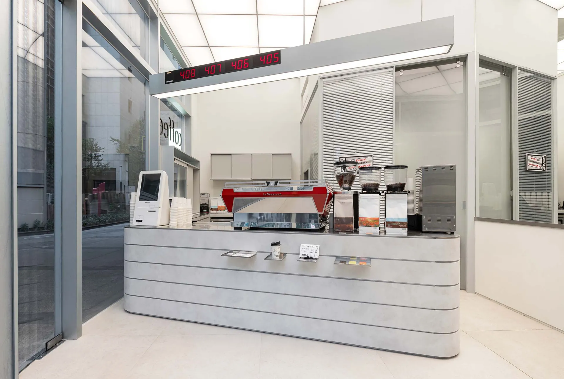 A modern coffee shop with a metal counter, large window, and natural light, creating a welcoming atmosphere