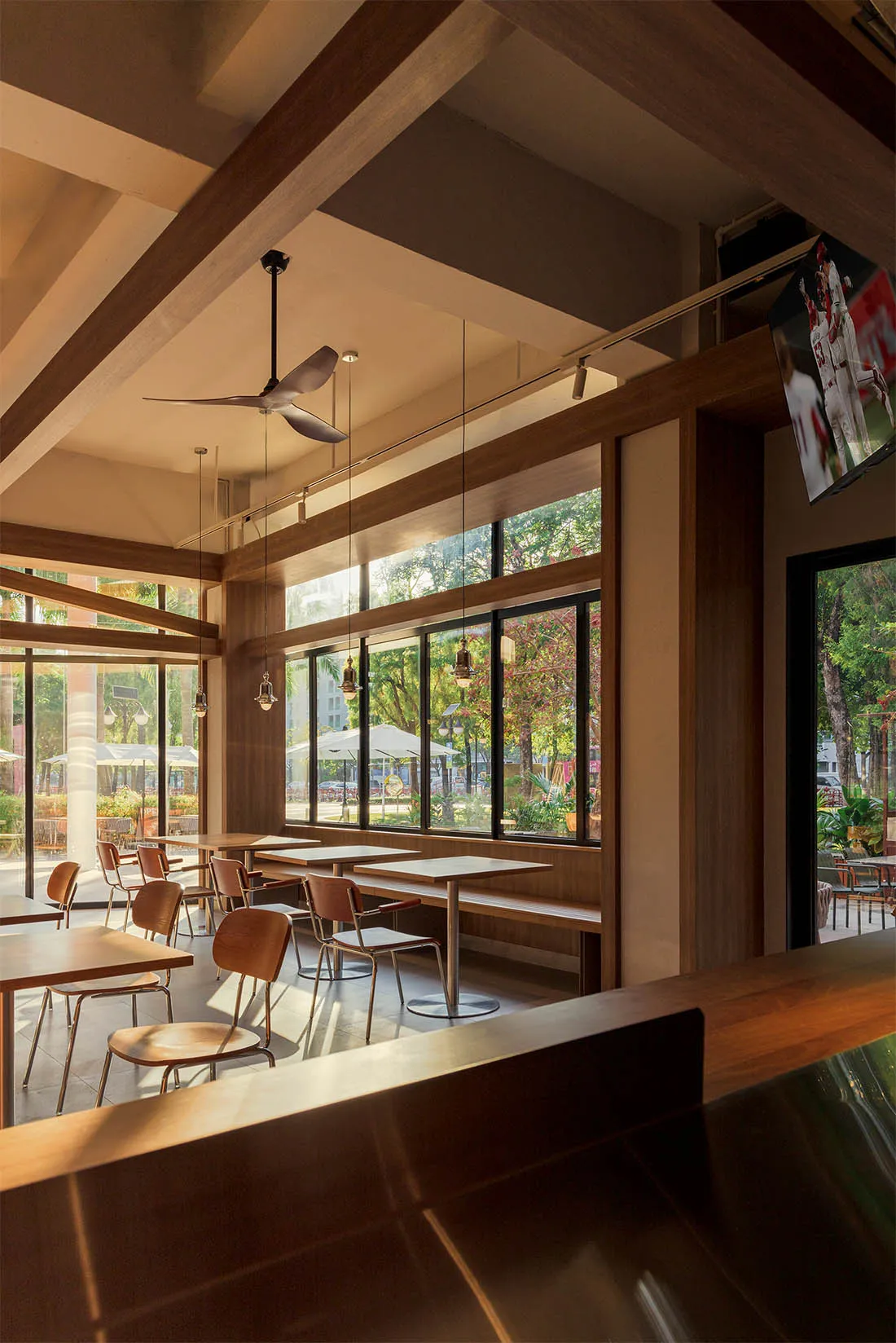 A modern restaurant interior with a dining area and bar, featuring wooden elements, soft warm lighting, and a contemporary color scheme