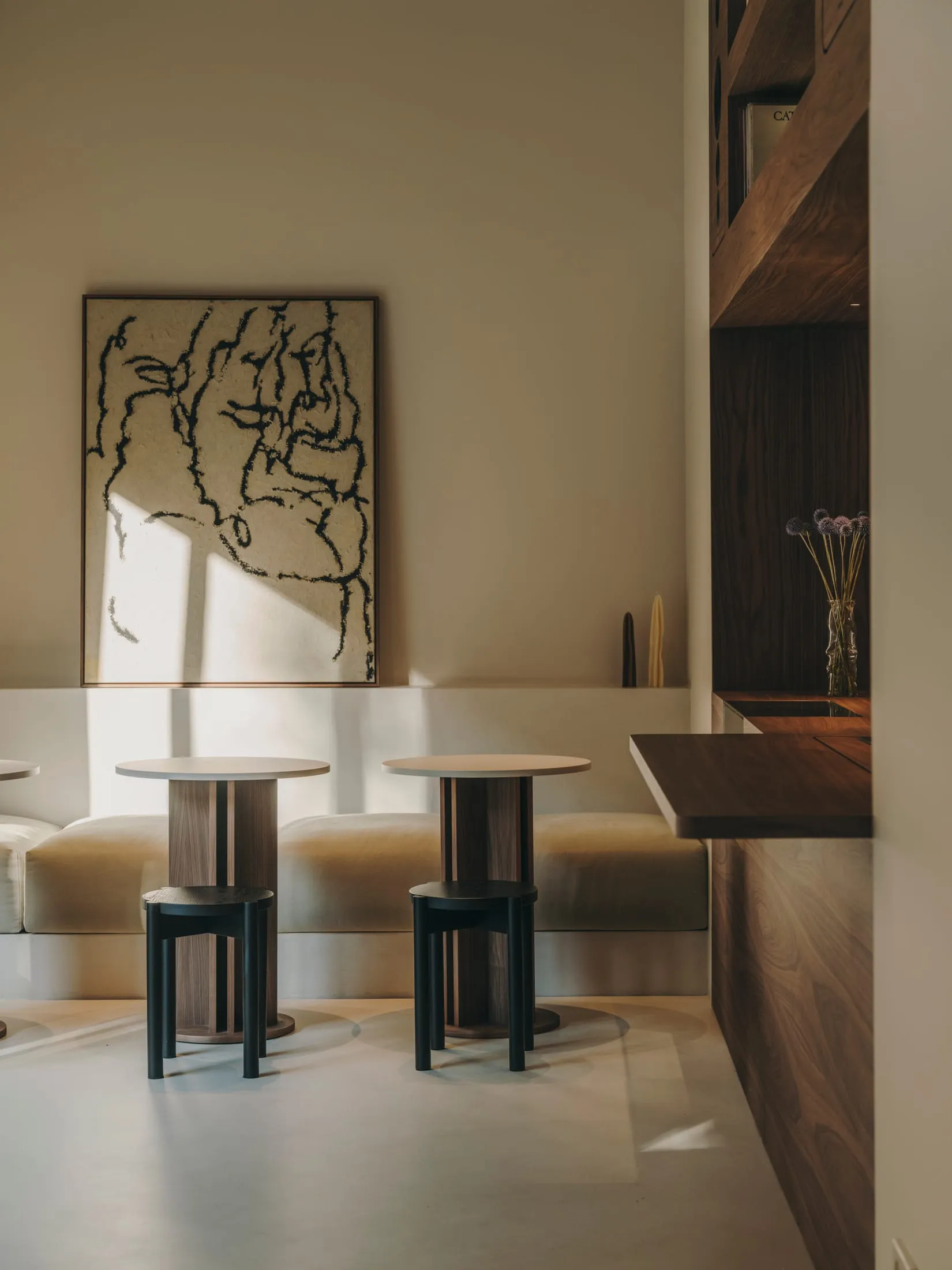 A modern living room with a large painting, two couches, a dining table, and several chairs, set in a well-lit space with a contemporary style