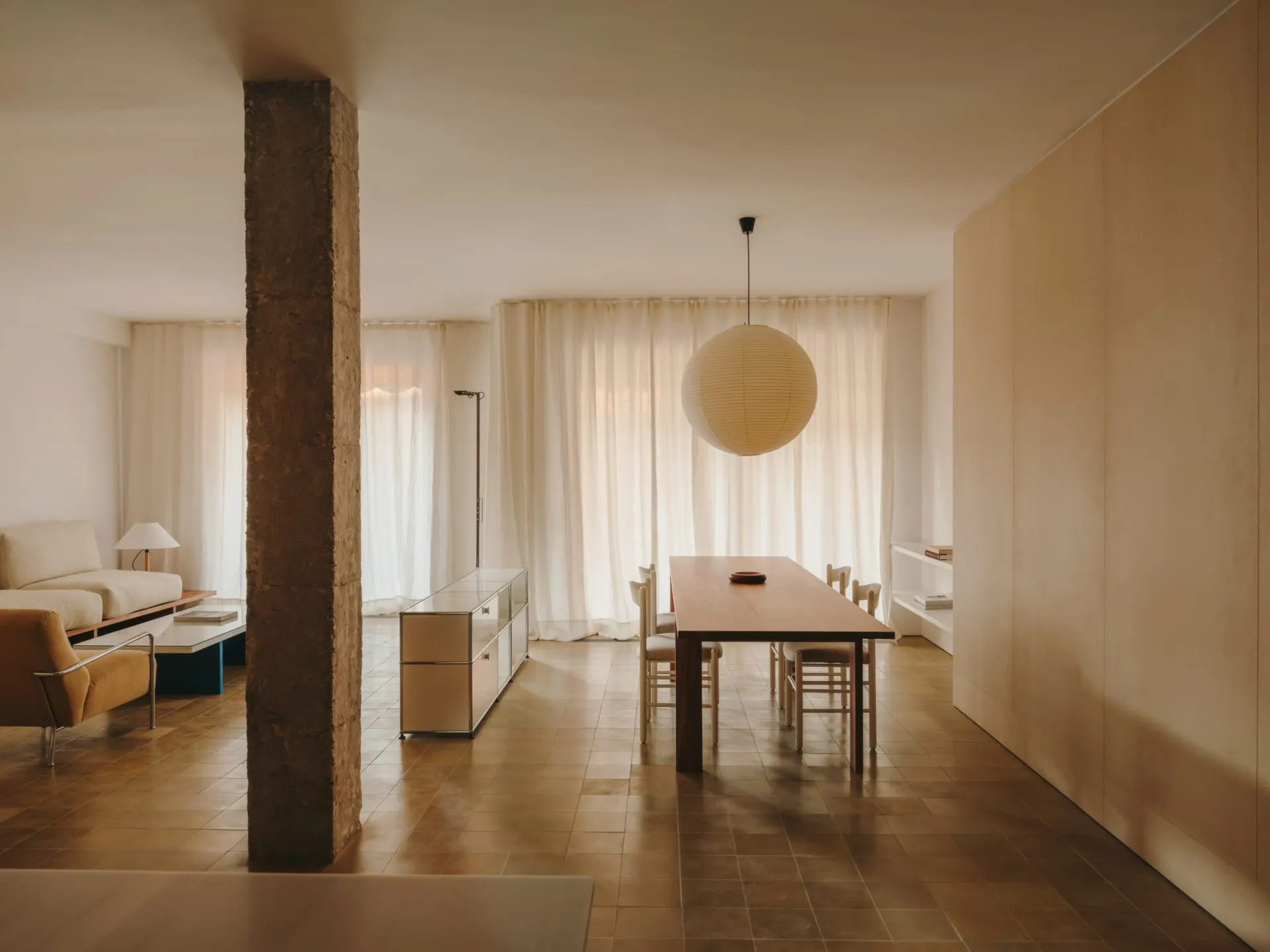 Modern living room with a dining area, featuring a couch, chair, dining table, and various furniture, illuminated by natural light, with a focus on functionality and comfort