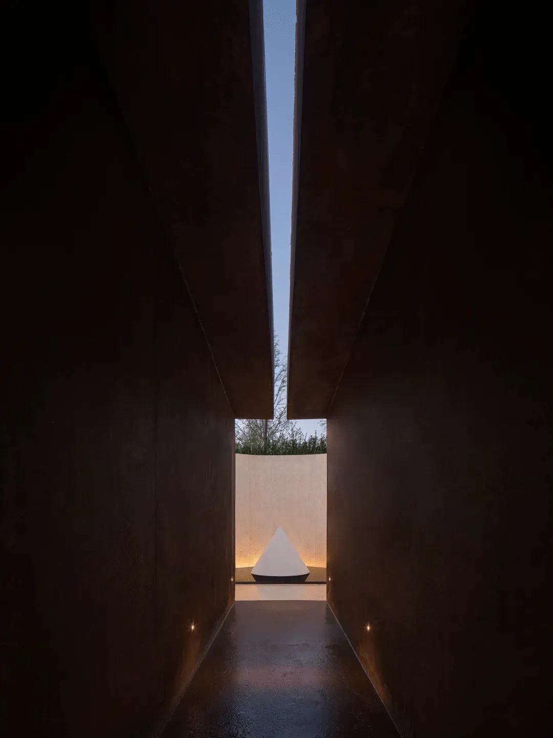 A dark room with a small white triangle on the floor, creating a focal point in the space