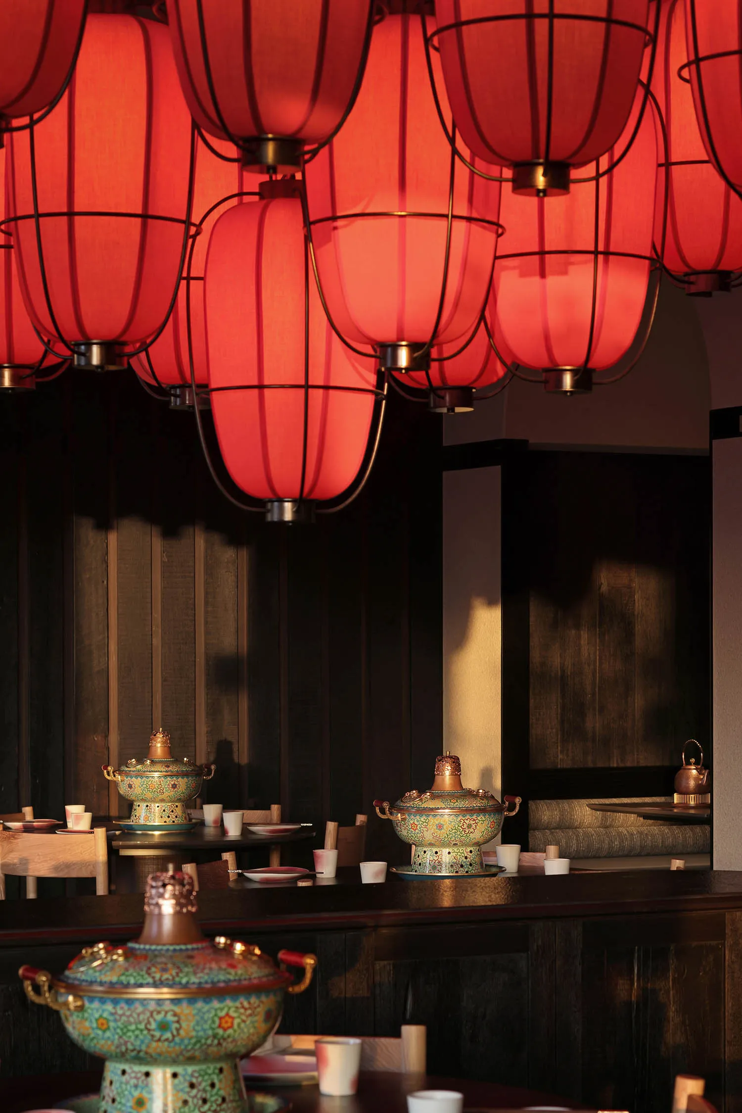 一間現代餐廳的用餐區域，擺放著一長條木製餐桌和椅子，周圍擺放著陶瓷碗和杯子，氛圍溫暖親切