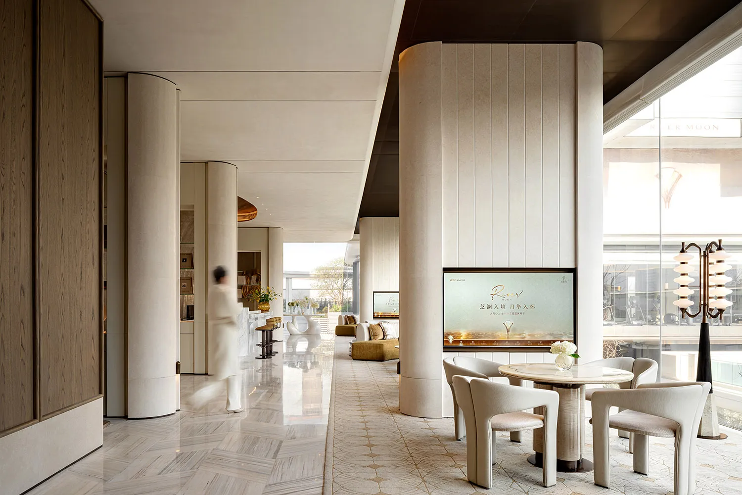 Well-lit lobby with a large TV, comfortable seating, decorative elements, and a sophisticated atmosphere