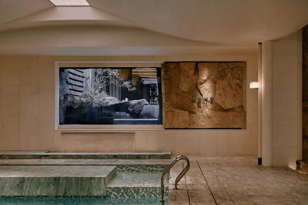 Bathroom with a large window, a pool, and a stone wall, featuring modern design and natural light