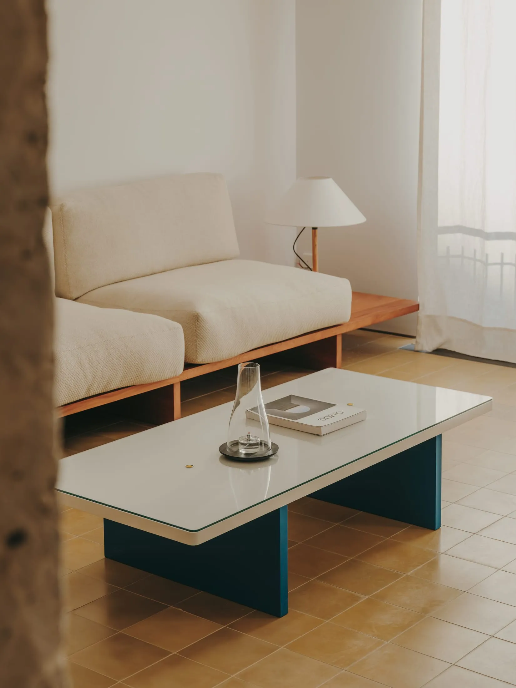 A modern living room with a blue sofa, glass coffee table, and neutral color palette, featuring clean lines and simple design