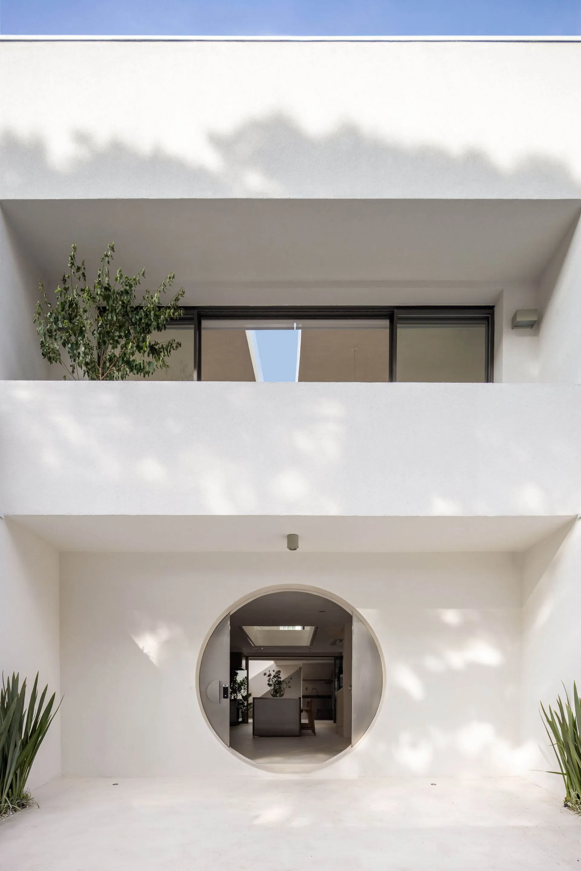A bright and inviting living room with a modern house featuring a circular window and a potted plant, well-lit with a warm atmosphere