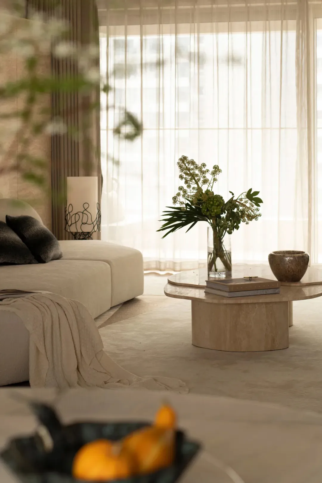 A well-lit living room with a white couch, coffee table, and a vase with flowers, showcasing modern simplicity and functionality
