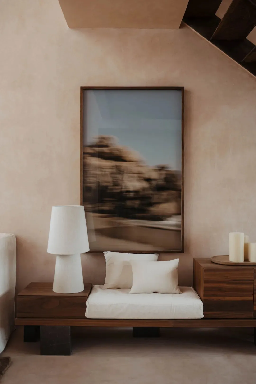A modern bedroom with a bed, bench, and lamp, featuring wood and metal furniture in a neutral color palette, set in a well-lit and inviting space