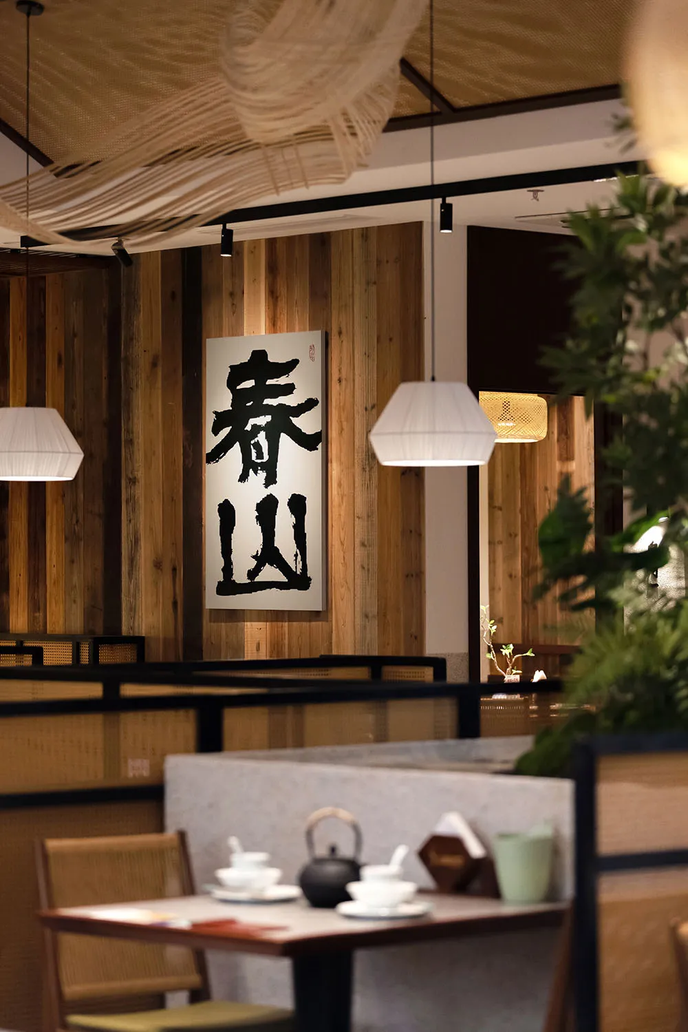 一間現代餐廳的室內裝潢，木板牆、充足照明，社交用餐的桌子和椅子