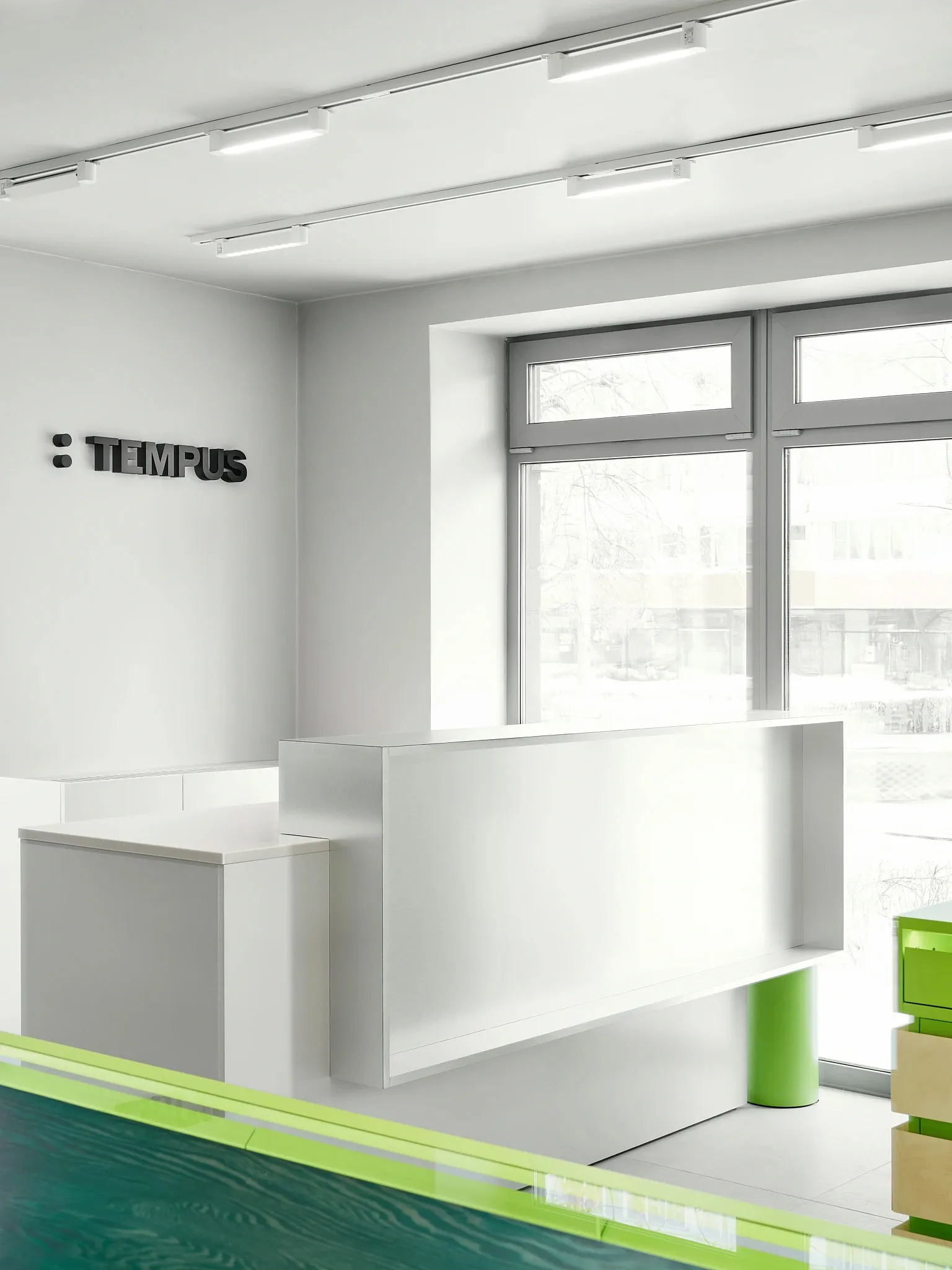 A well-lit office space with a white desk, counter, and chair, featuring a predominantly white color scheme and modern aesthetic