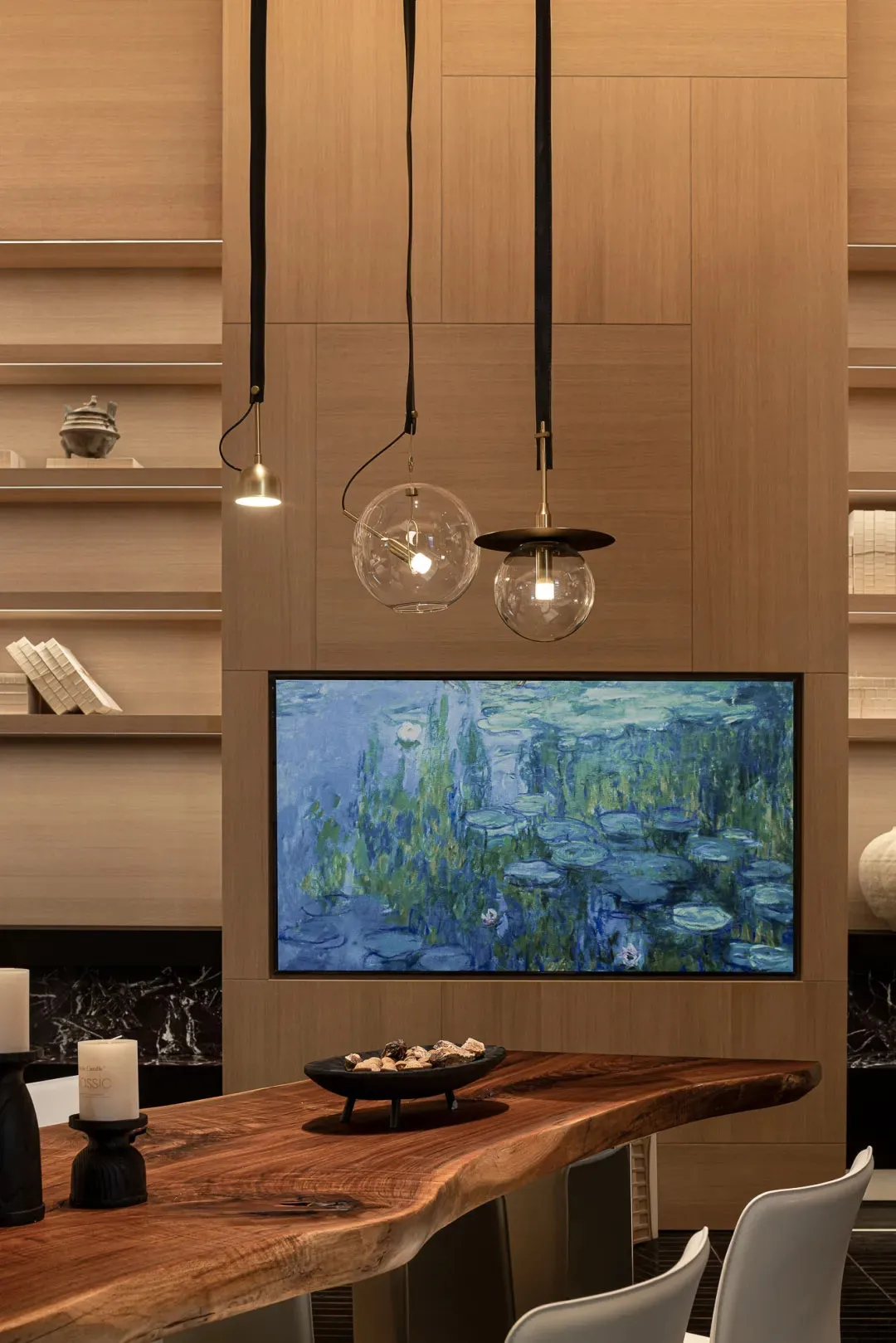 A modern living room with wooden walls and a wooden table, featuring a flat screen TV, books, and a bowl, with balanced lighting creating a comfortable atmosphere