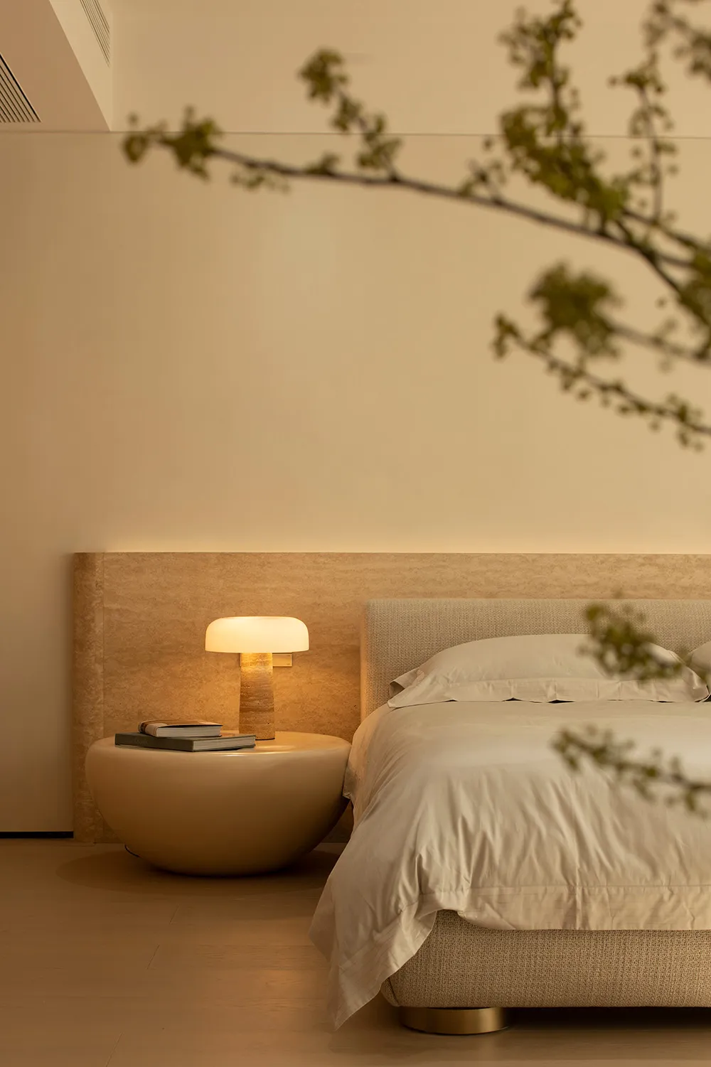 A cozy bedroom with a wooden bed, a table lamp, and a book, featuring soft and warm lighting and inviting atmosphere