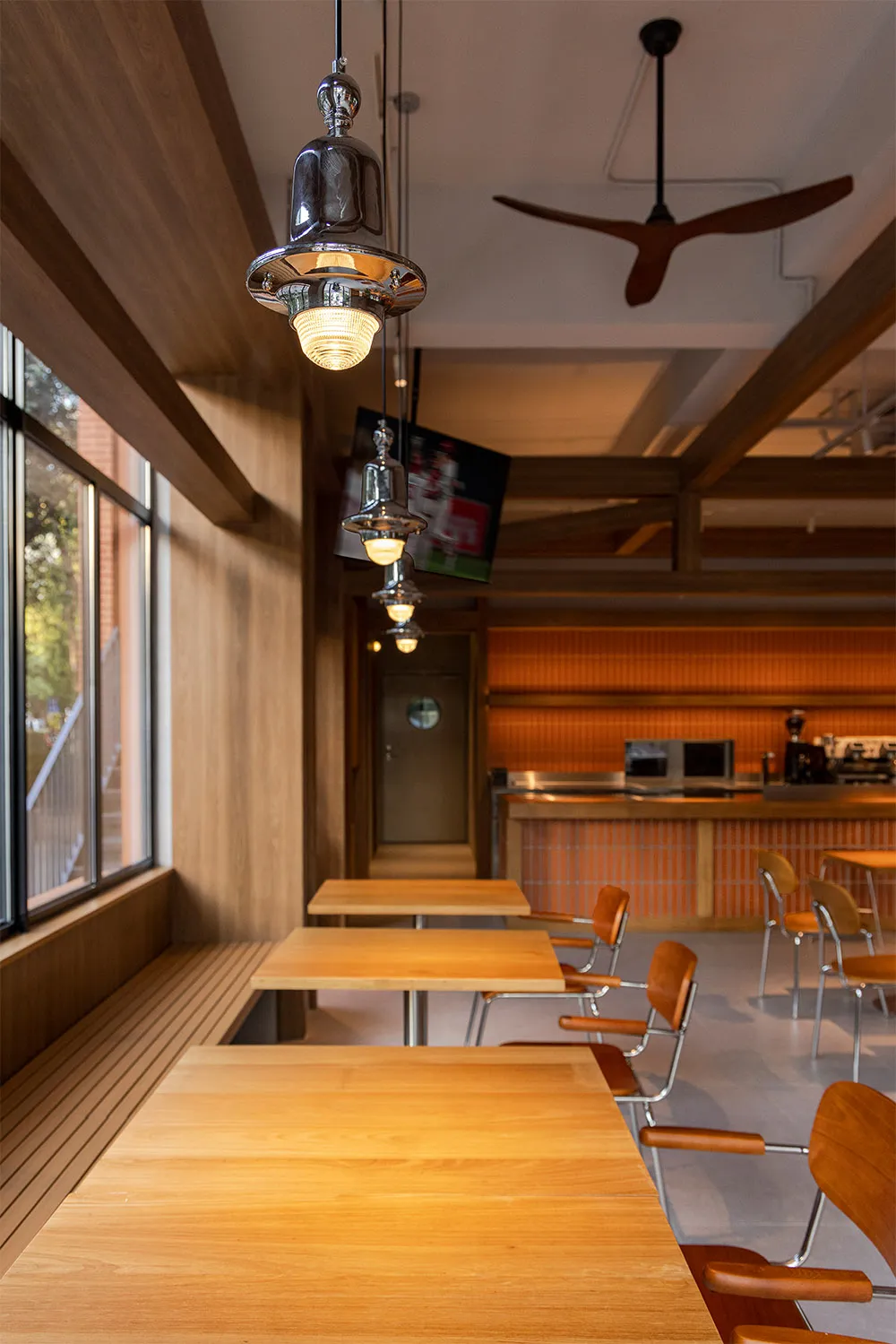 Warm and inviting dining space with wooden tables, chairs, and a TV, surrounded by natural light