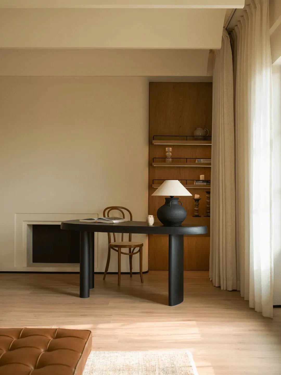 A modern dining room with a wooden floor, a black table, and chairs, featuring a lamp and a sleek contemporary style