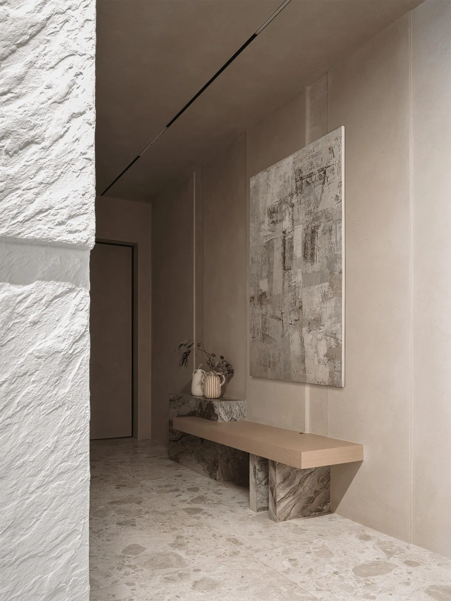 A dimly lit living space with a wooden bench and a painting on the wall, featuring a simple and minimalistic design