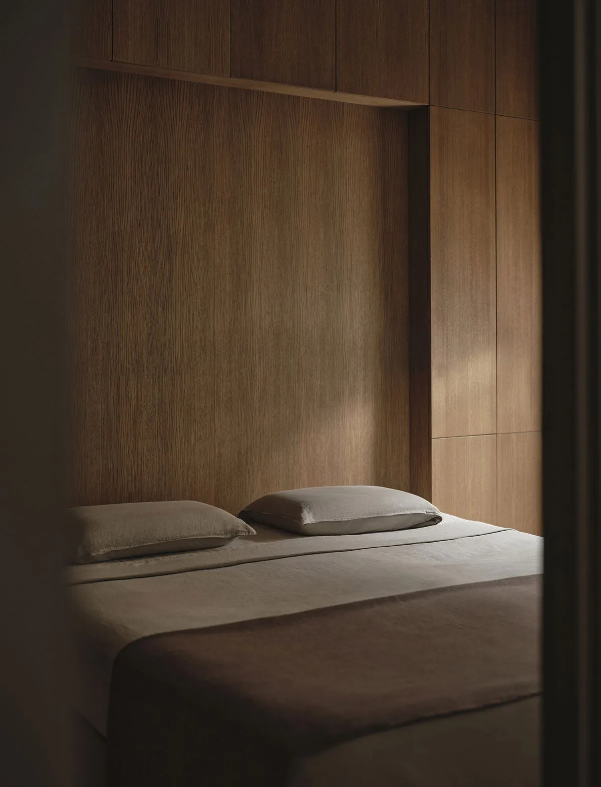 Cozy bedroom with a brown wooden wall, a white bed, and natural soft lighting