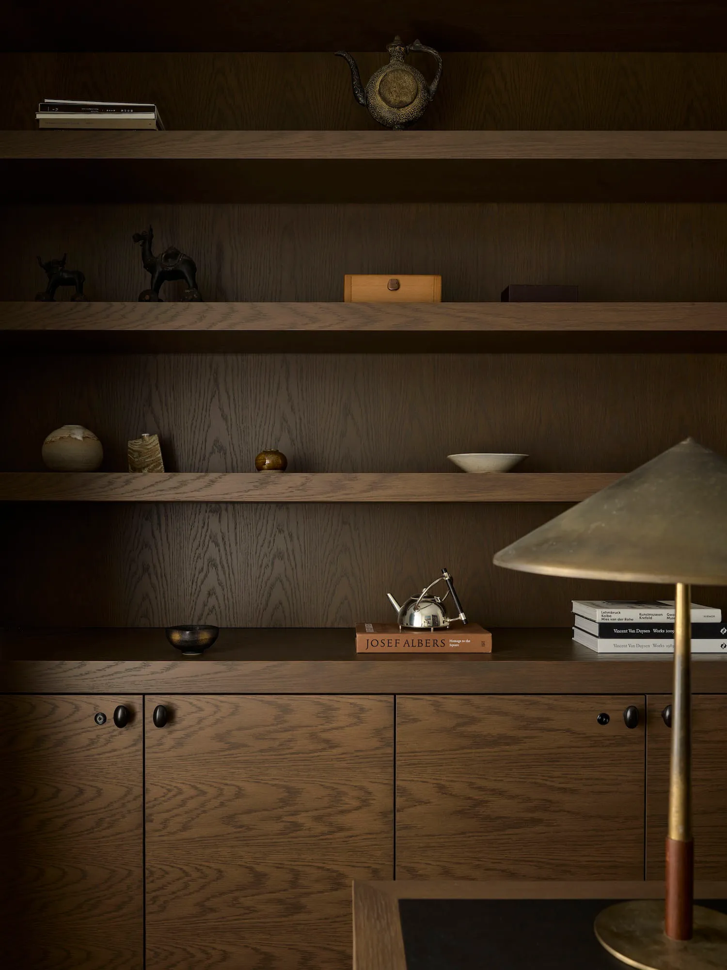 Cozy living space with wooden shelves and a table, featuring a warm and inviting atmosphere with a lamp and decorative items