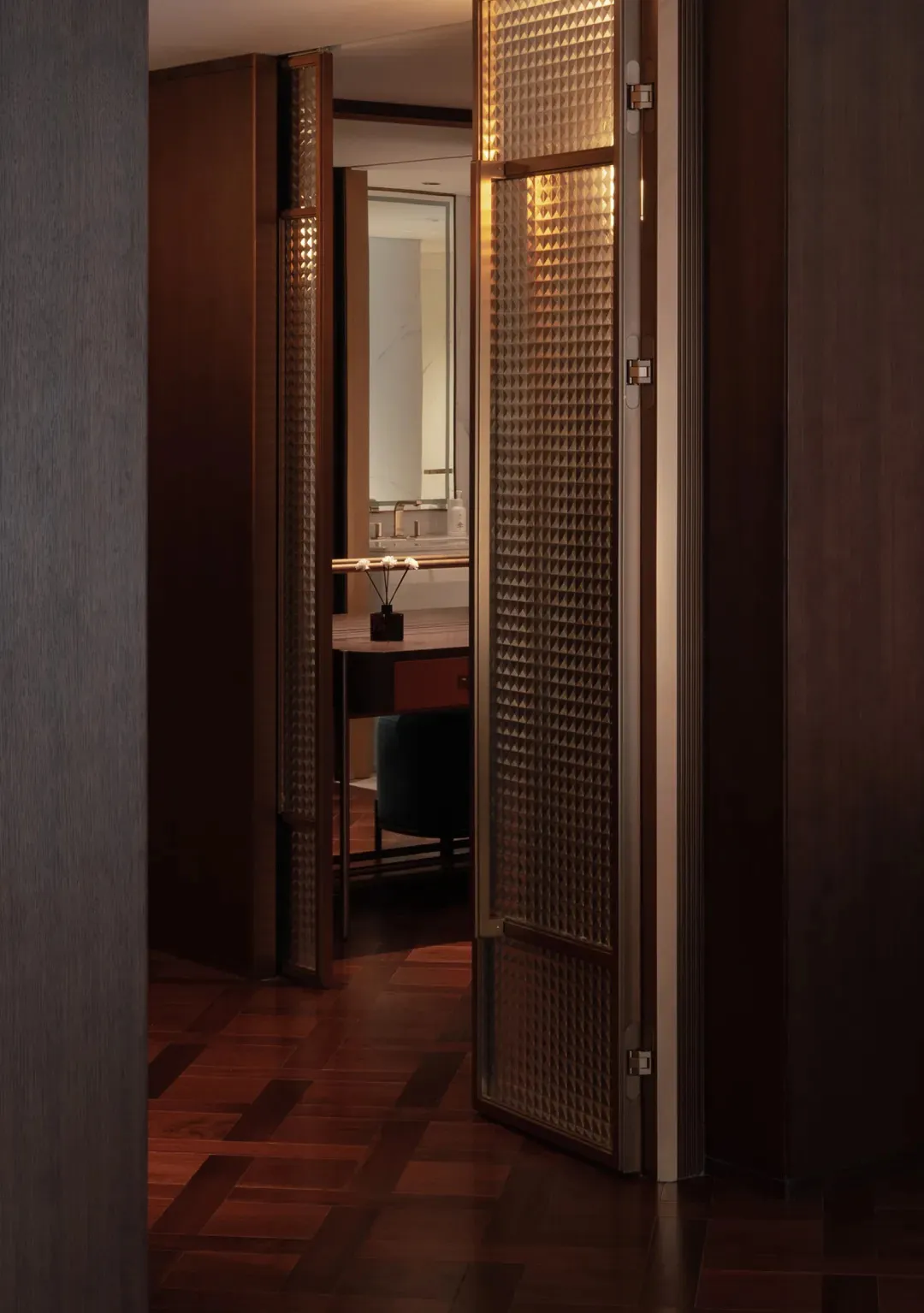 Bathroom with a wooden floor, sink, mirror, and open door, featuring dim lighting and a cozy atmosphere