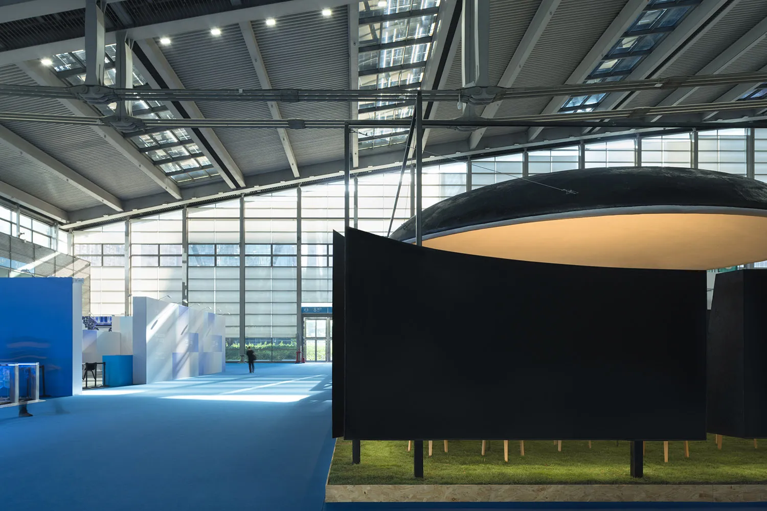 A modern art gallery with a black wall, glass dome, and various sculptures on display