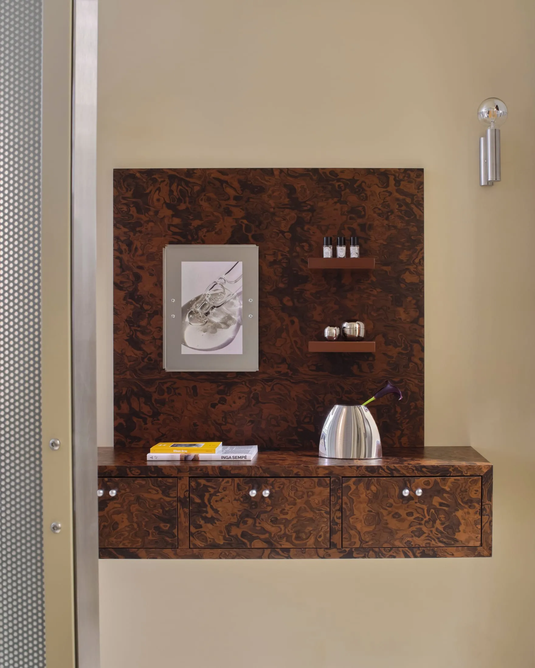 Bathroom with a wooden cabinet, mirror, and picture on the wall, featuring a warm brown and tan color scheme and natural lighting