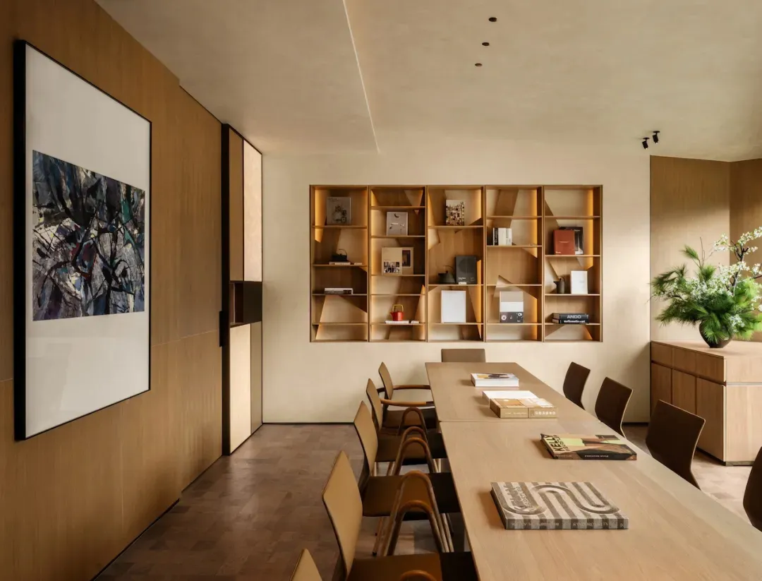 A well-used conference room with a wooden table and chairs, surrounded by books and magazines, creating a comfortable space for gatherings or meetings
