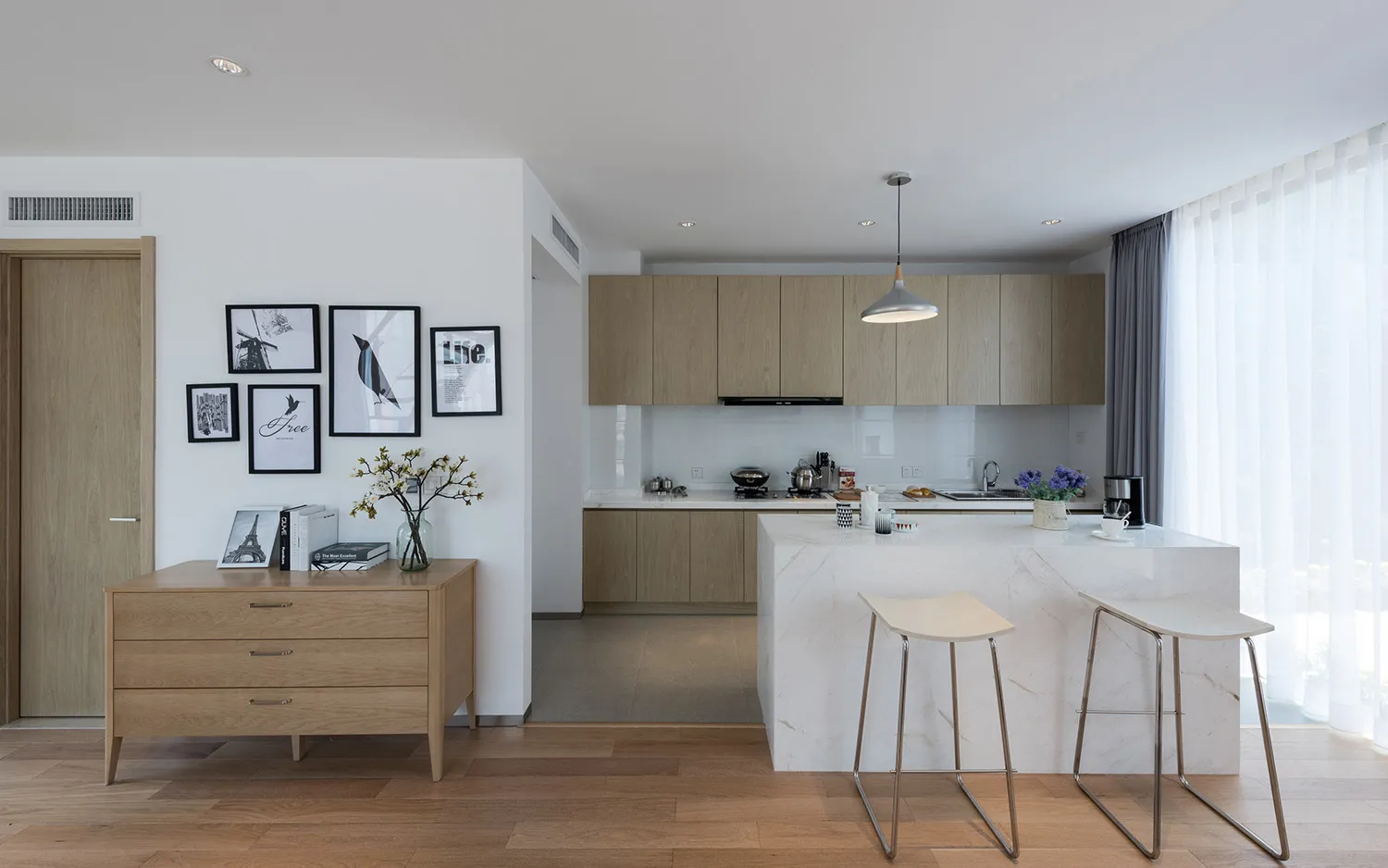 Bright and inviting modern kitchen and dining space with a marble countertop, wooden table, and black oven