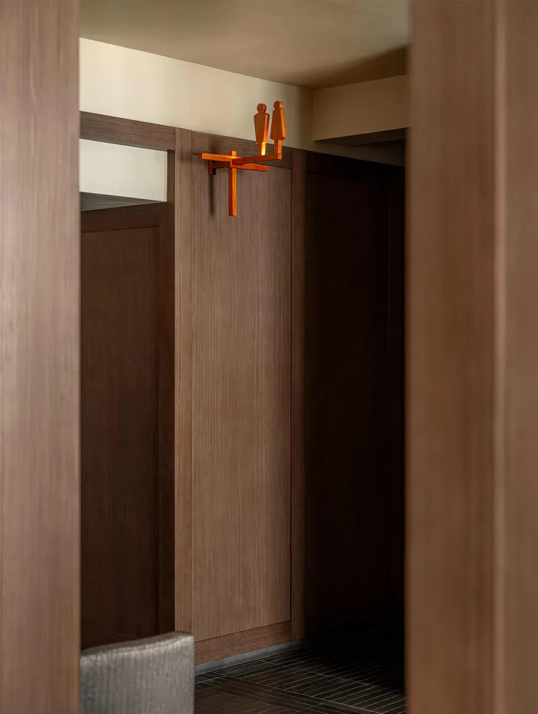 Warm and intimate bathroom with wooden walls, a wooden door, and a wooden cabinet in a brown color scheme, with dim lighting