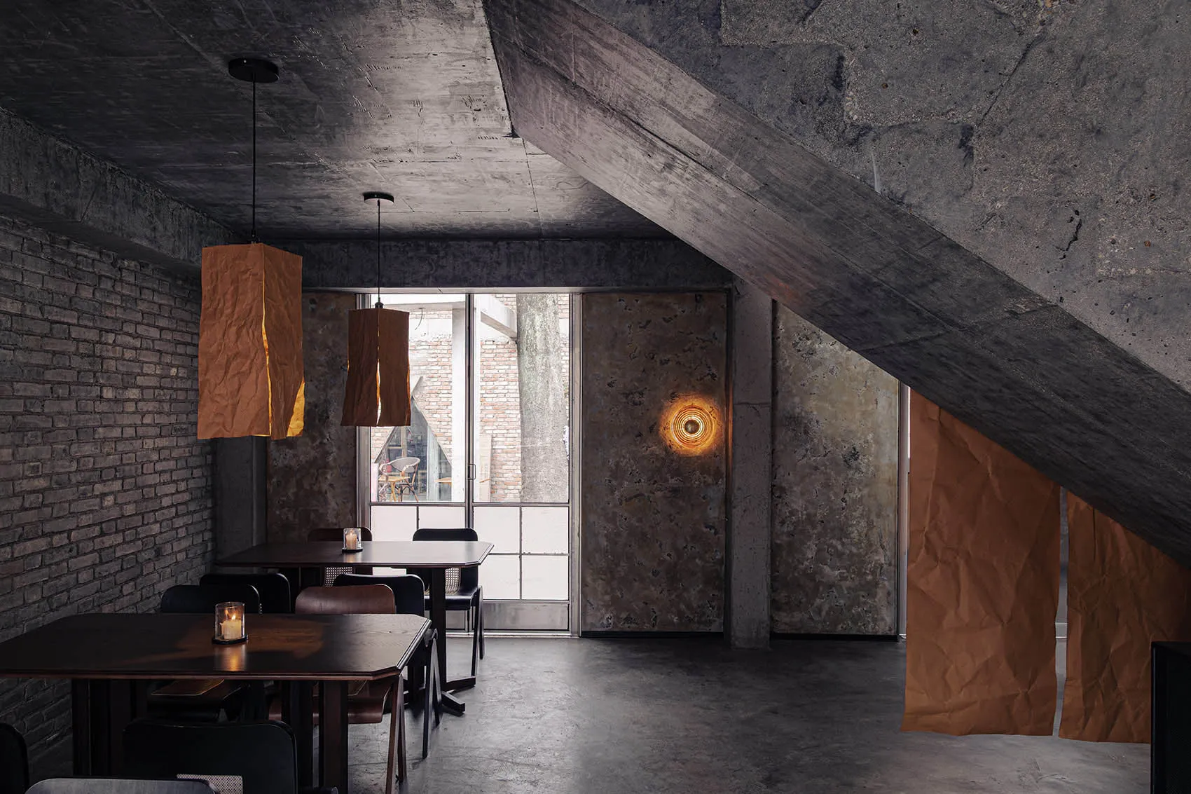 Cozy restaurant with a modern design, featuring a dining area, bar, wood, and concrete elements, with dim lighting and natural light from windows