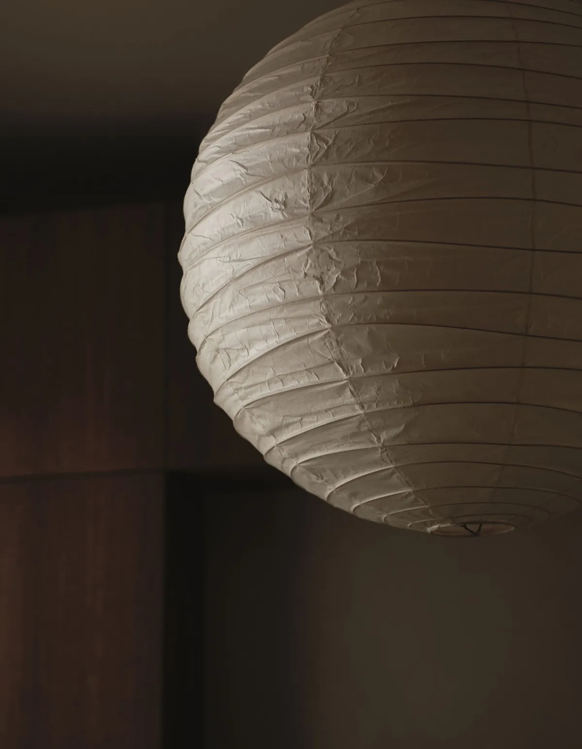 A dimly lit room with a unique paper lamp hanging from the ceiling, the focus is on the lamp