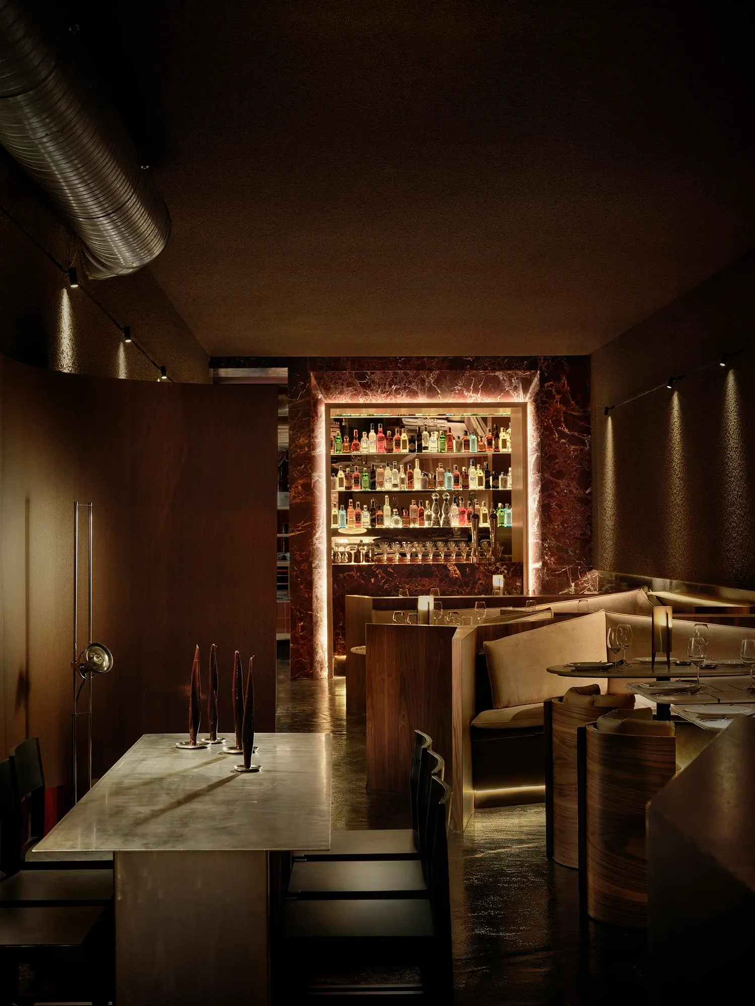 A well-lit restaurant interior with a wooden bar, marble surfaces, and comfortable seating areas