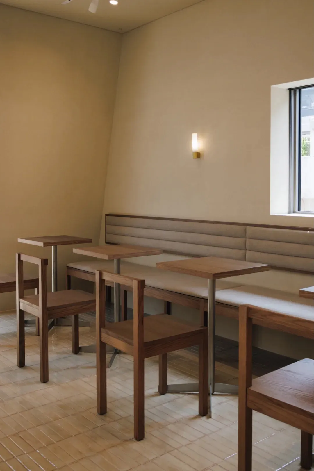 Cozy dining space with a wooden floor, white walls, and natural light from a window, featuring a bench and chairs around a dining table