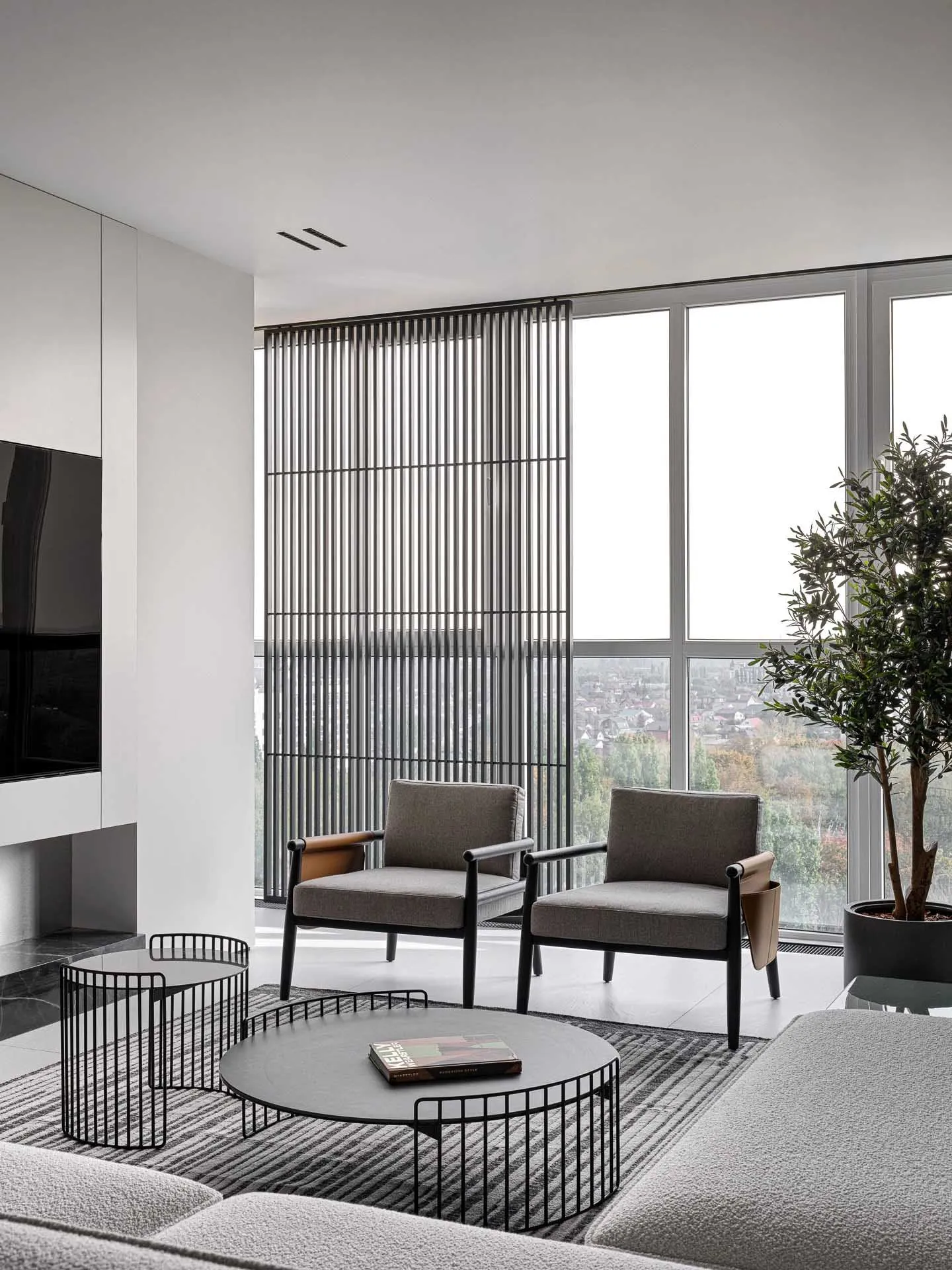 A well-lit, modern living room with a large window, grey furniture, and a potted plant, featuring wood and glass materials
