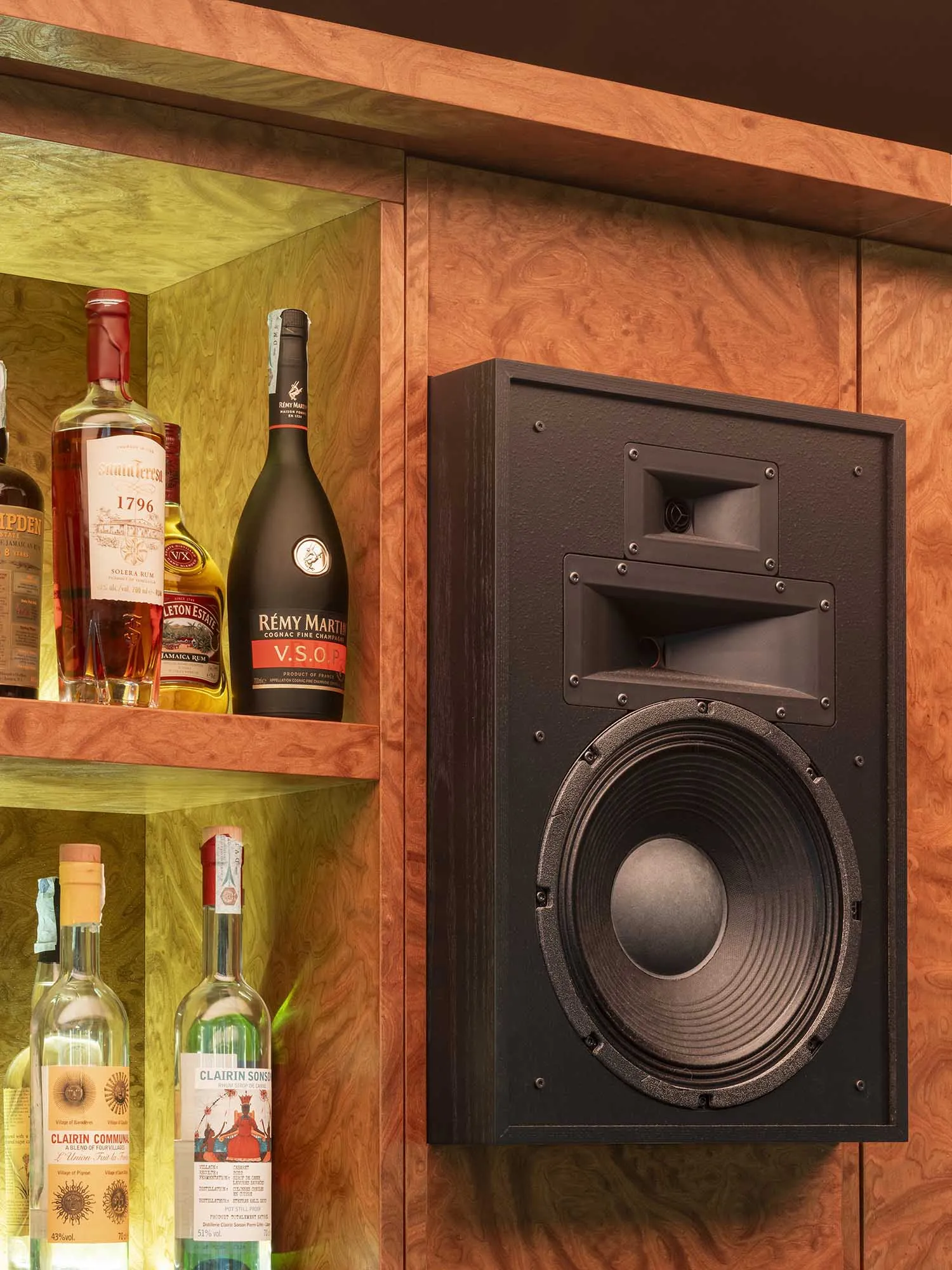 A bar with a wooden shelf and a collection of liquor bottles, creating a warm and welcoming environment