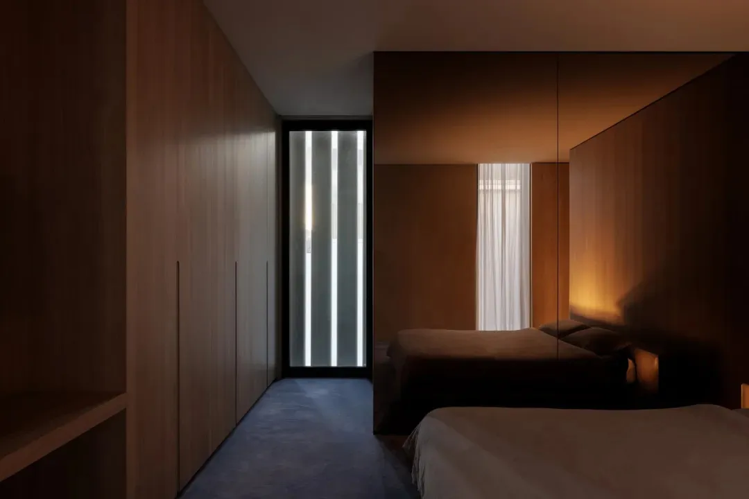 Cozy bedroom with a wooden floor, a bed, a closet, and a window, dimly lit