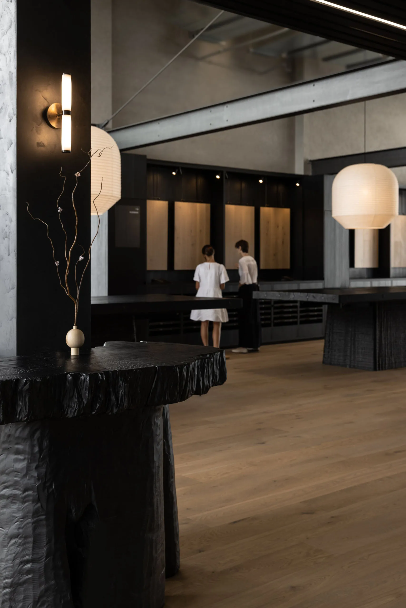 A modern restaurant interior with a wooden floor, dining table, and chairs, surrounded by people enjoying meals and conversations in a warm and inviting atmosphere