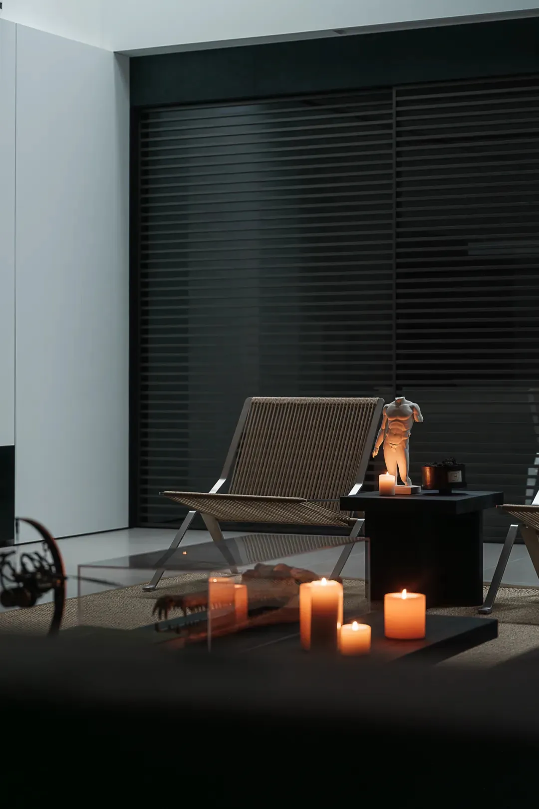 A well-lit living room with a glass table, wooden furniture, and a comfortable ambiance created by candlelight