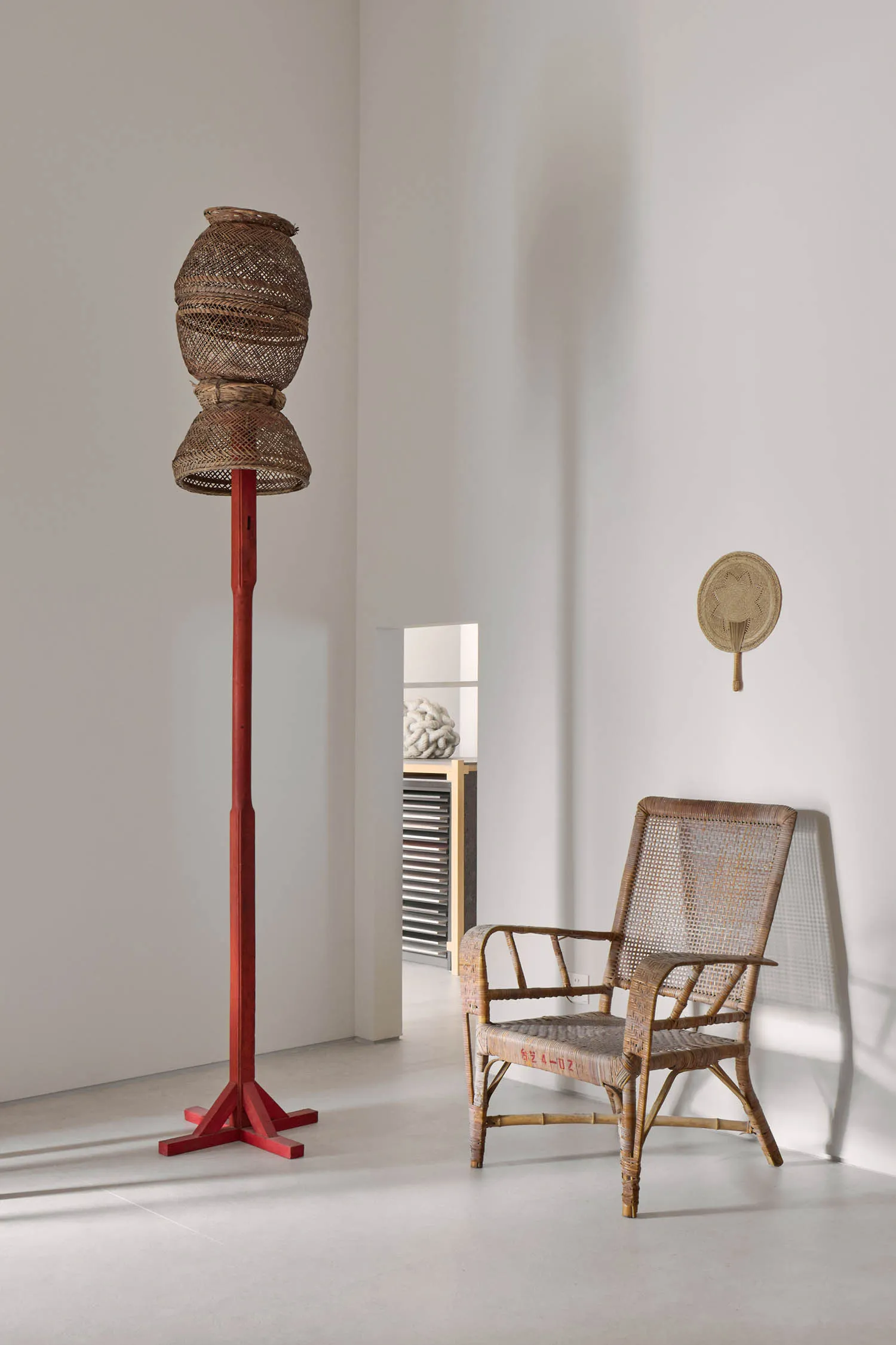 A dimly lit living space with a wooden chair and table, surrounded by a white wall and a red pole