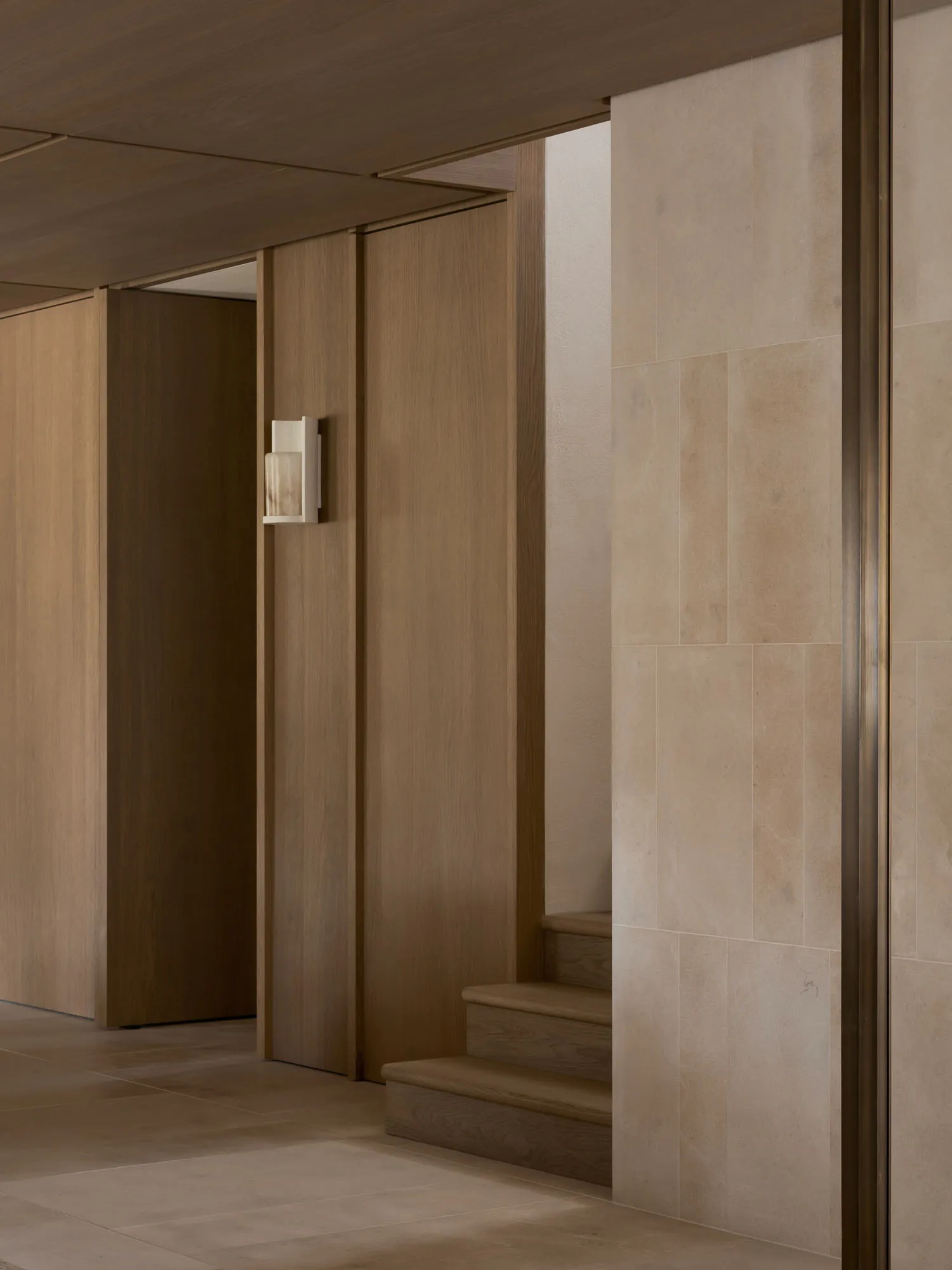 A dark and gloomy hallway with wooden walls, lined with doors and a light on the wall