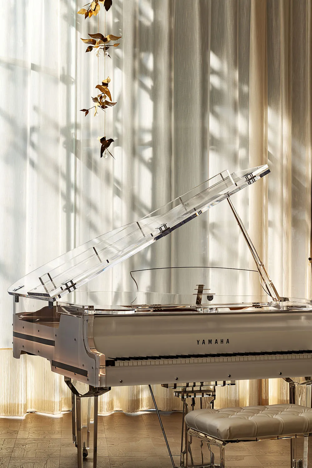 A calm and serene living space with a white piano and clear glass top, lit by natural light from a window