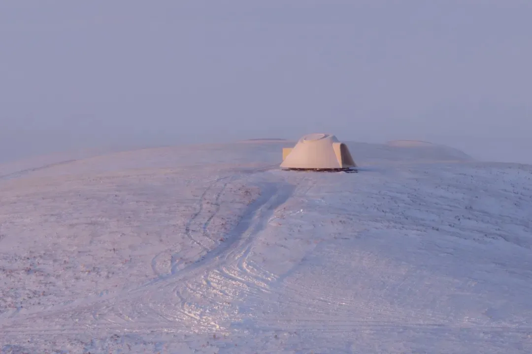 一片靜謐的雪景色中，半圓形的小屋突出在白色背景中