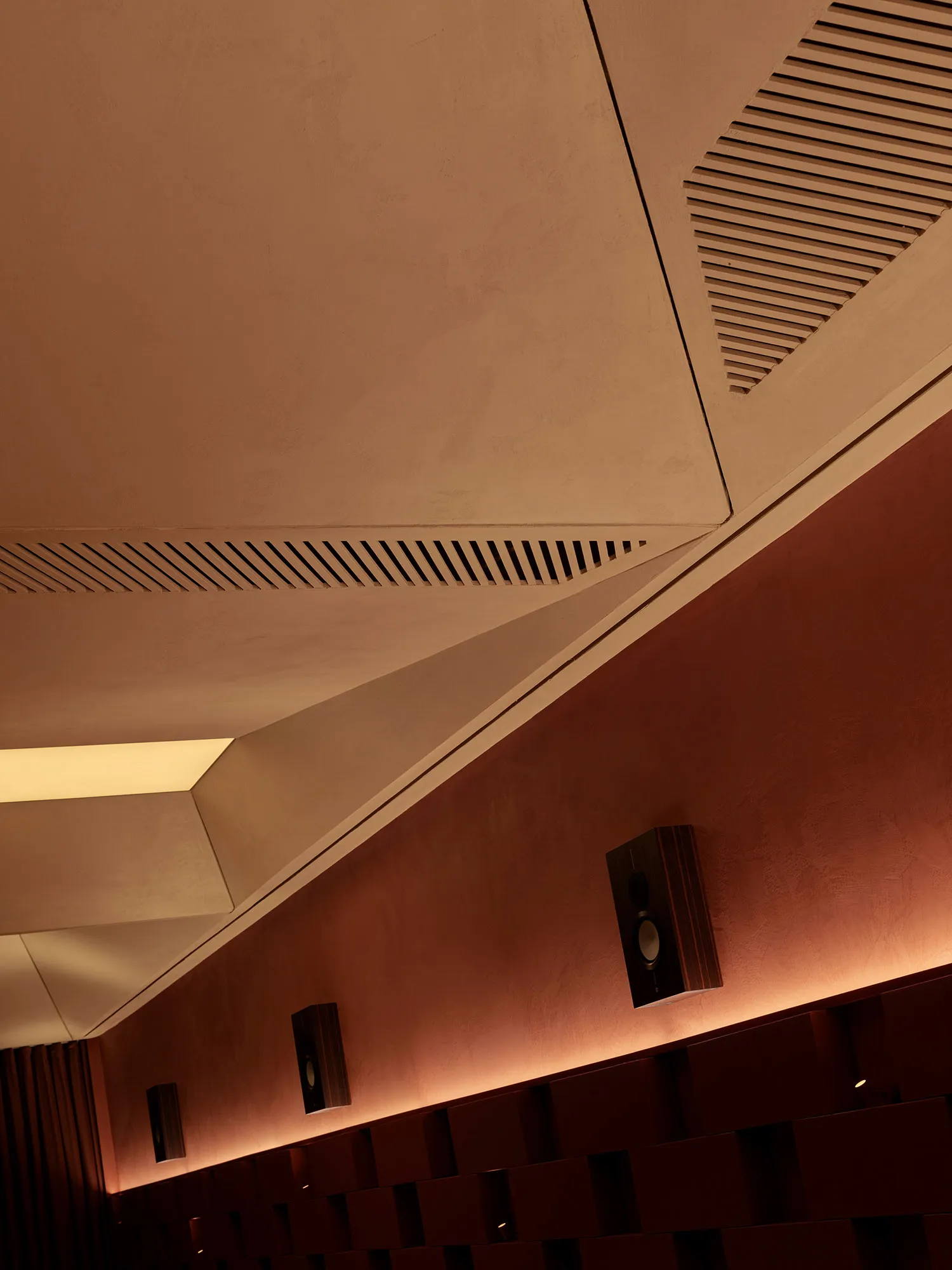 A small, dark room with a red wall and speakers on the left and right sides