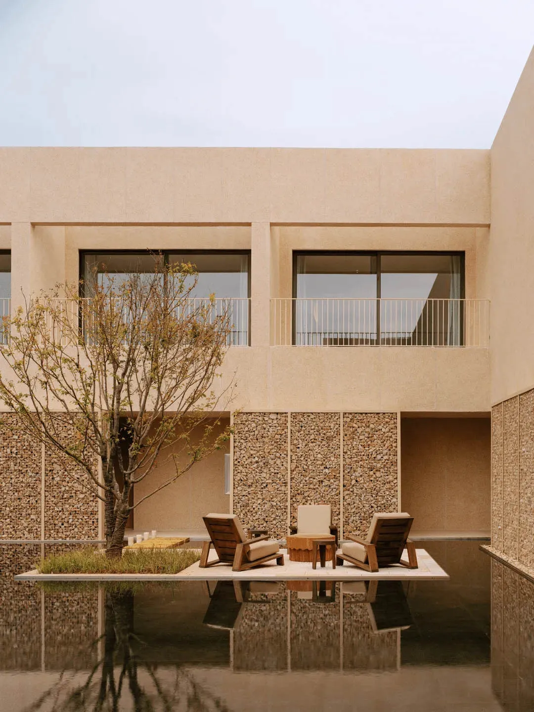 A modern patio with a table and chairs surrounded by a concrete base, with a bench nearby, and natural sunlight creating a warm atmosphere