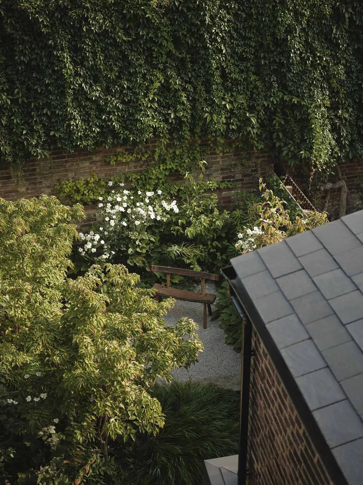 a well-maintained garden with a bench and a brick wall in the background
