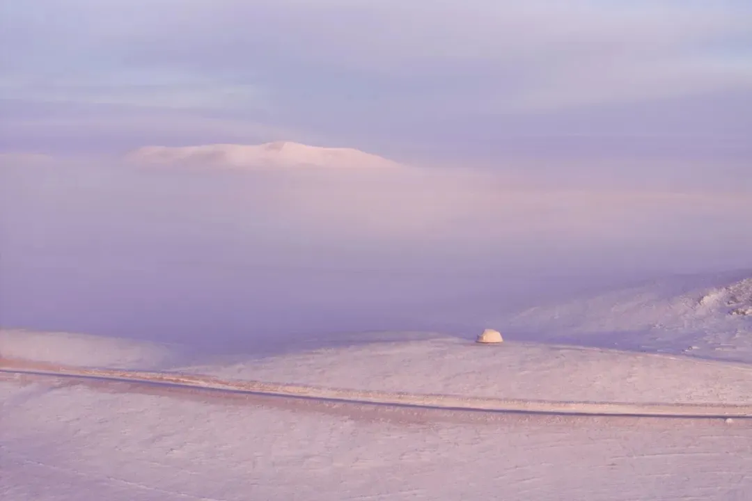 靜靜的雪景景色裡面有個原始木頭的山屋在前景，周圍被覆蓋著雪的山坡