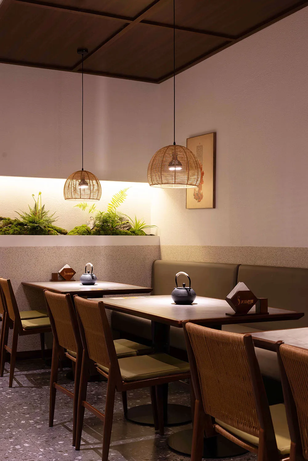 Cozy modern restaurant interior with dim lighting, artwork on the walls, and tables set with bowls and cups