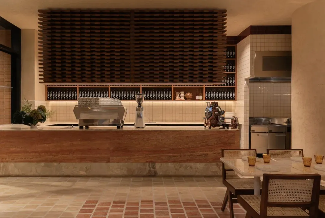 Cozy restaurant interior with a brick wall, bar, and dining area, featuring a counter with a coffee maker and blender, and a dining table with chairs