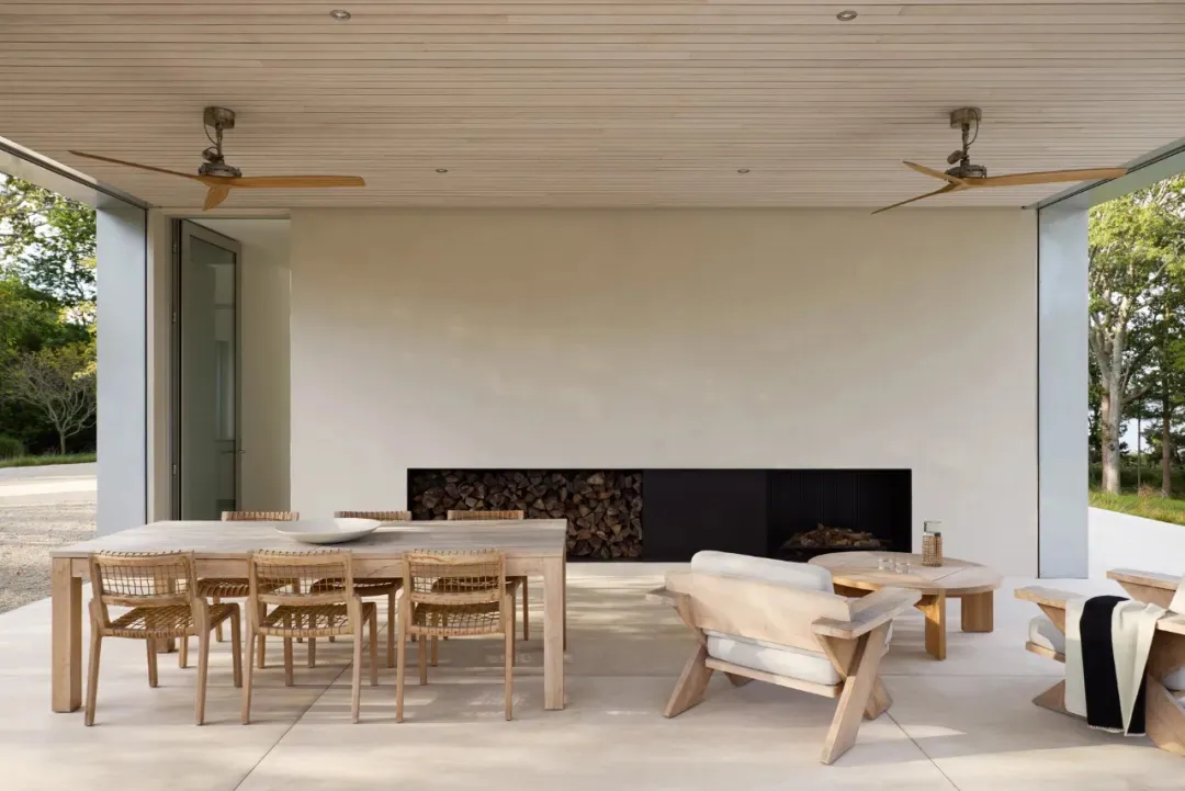 Cozy living room with a wooden floor, white walls, a dining table, chairs, a couch, and a fireplace, lit by natural sunlight