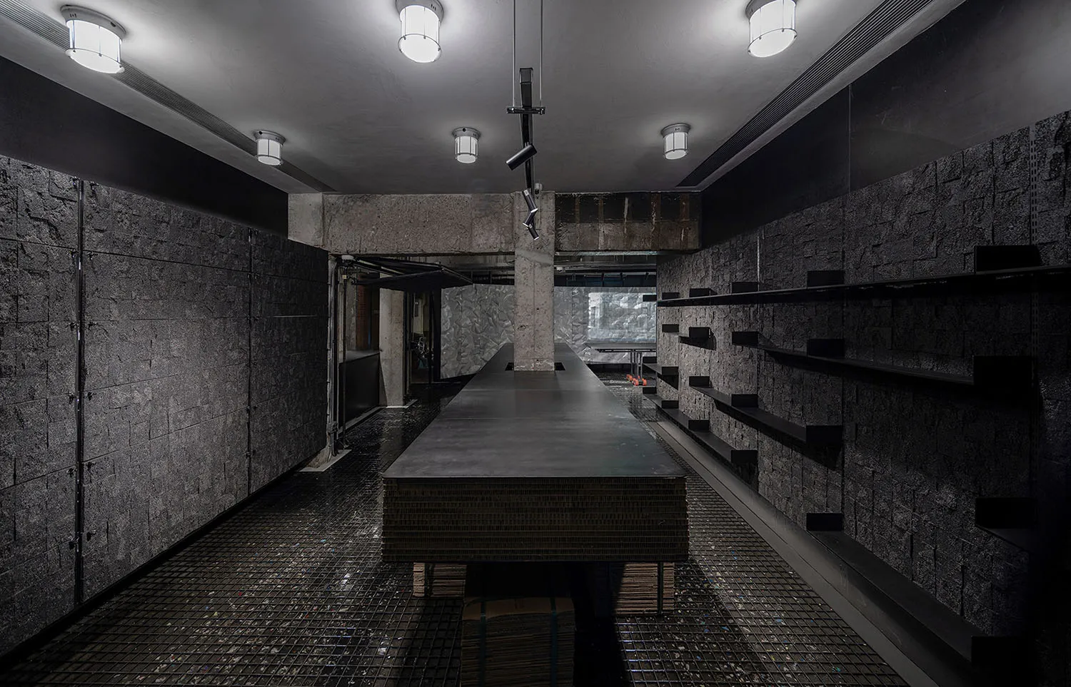 Modern kitchen with a dark countertop, a large window, and a dining table, featuring a sink and refrigerator, with dim lighting creating a cozy atmosphere