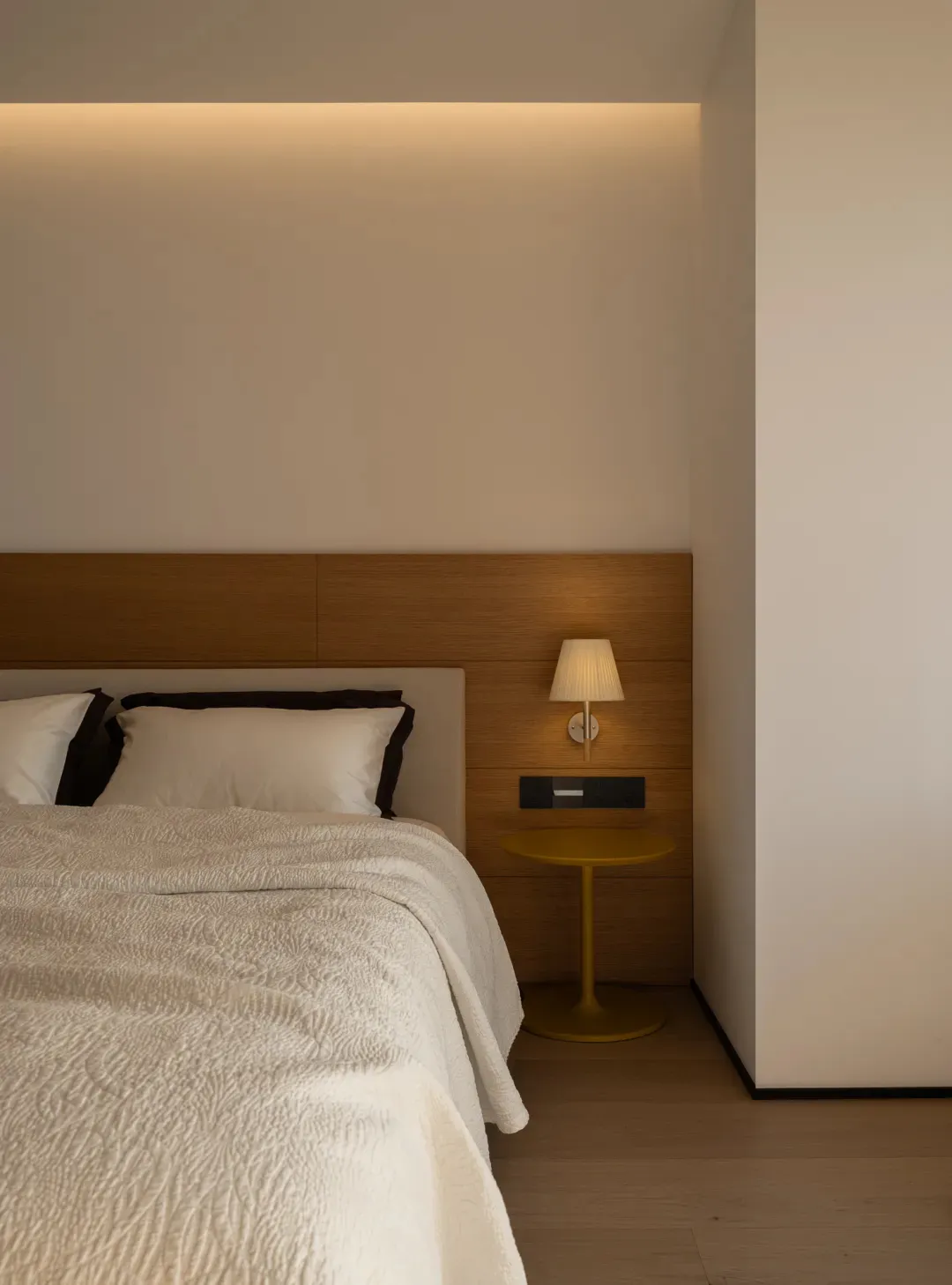 Cozy modern bedroom with a bed, wooden nightstand, and dim lighting