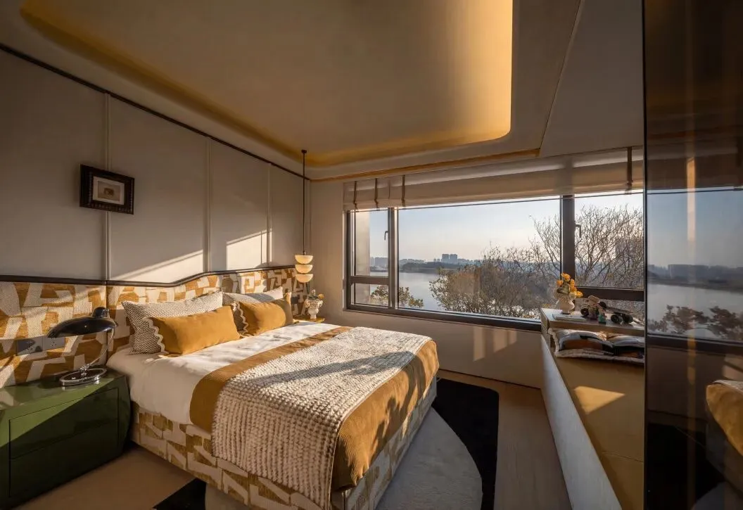 Cozy bedroom with a yellow color scheme, a white and brown blanket-covered bed, and a chair near a window with natural light